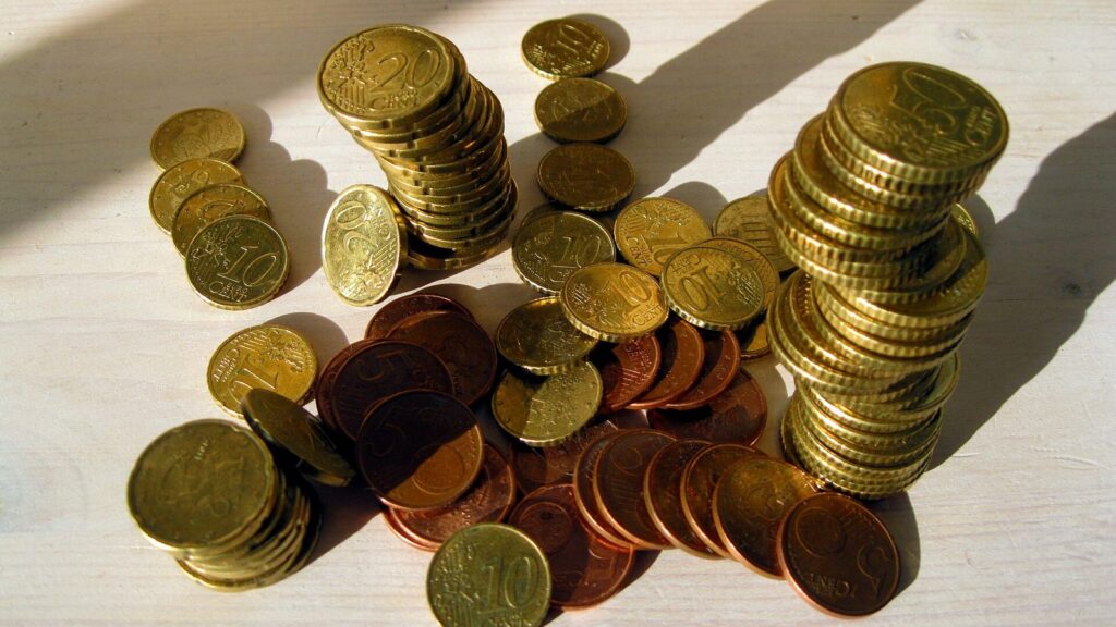 Monete in centesimi di euro sparse e impilate su un tavolo alla luce del sole