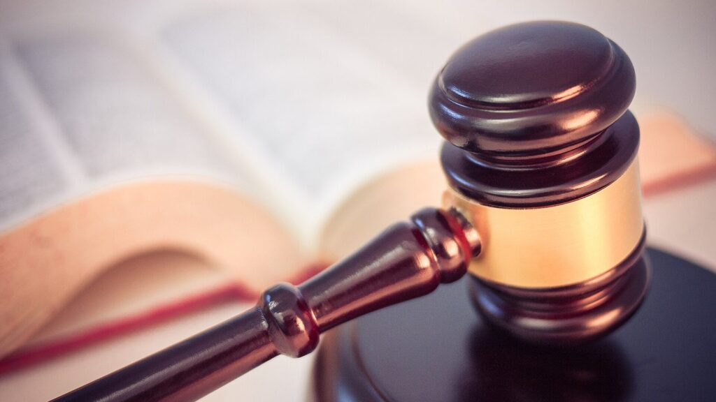 Martelletto del giudice appoggiato accanto a un codice aperto